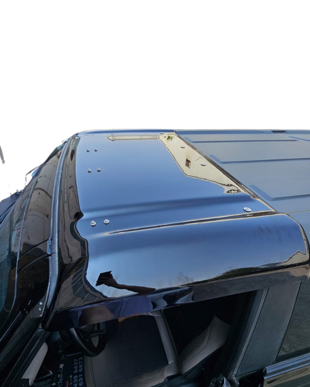 Close-up of a shiny black vehicle hood with reflections on a white background